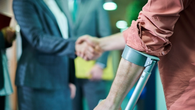 Injured person on crutches shaking hands with lawyer