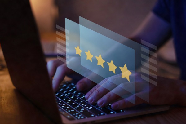 Person using laptop with five-star online review graphic.